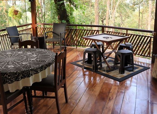 Outdoor dining area on a wooden deck overlooking a verdant landscape - BluSalzz Collection - Tranquil Resort, Wayanad
