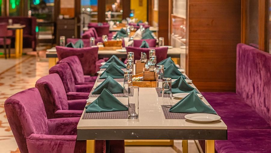 Cushioned chairs and a table set with exquisite culinary offerings for guests at Courtyard Fine Dine, Crescent Spa & Resort, Indore