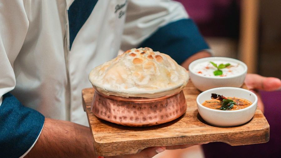 A chef serving delicious food to guests at Courtyard Fine Dine, Crescent Spa & Resort, Indore