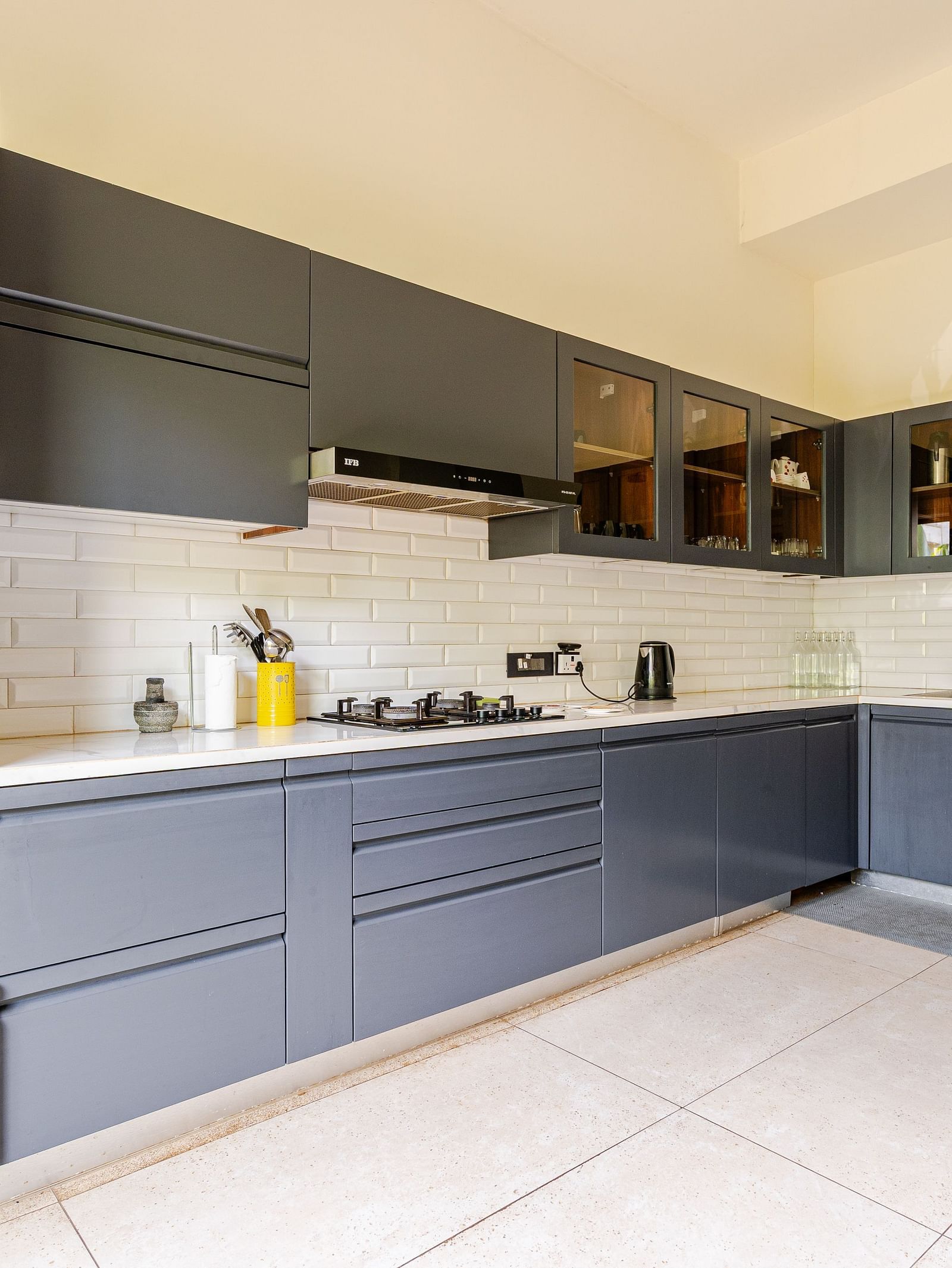Spacious modular kitchen at Lindsay Manor featuring built-in appliances, corner cabinetry, and white tiled flooring.