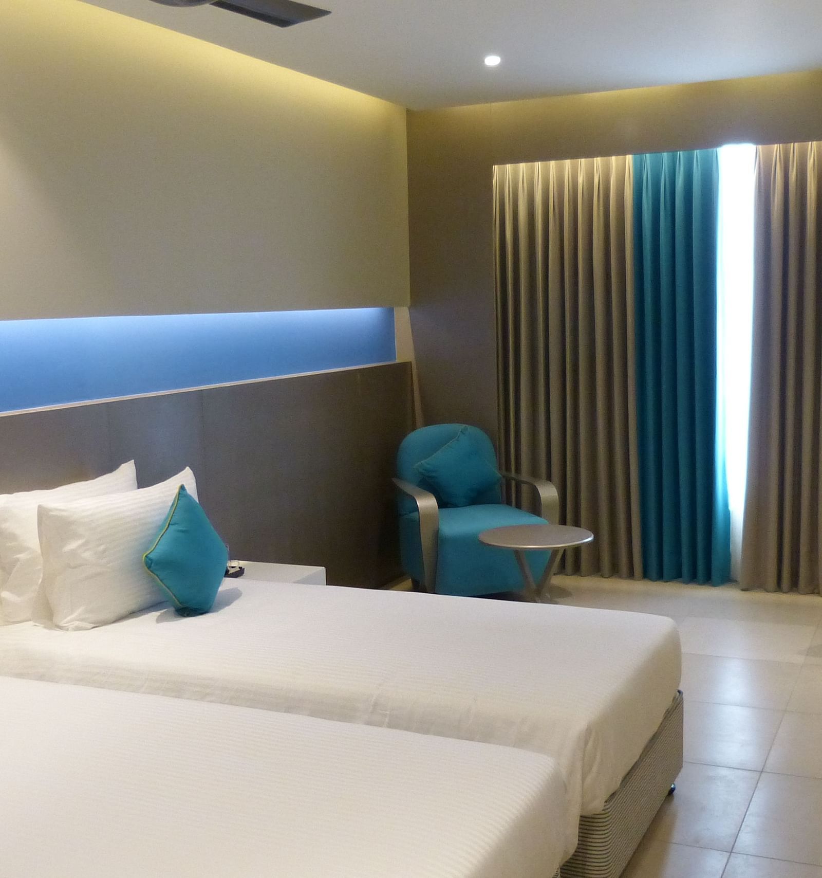  Spacious twin beds with headboards stretch across the wall, and large windows with curtains cover them