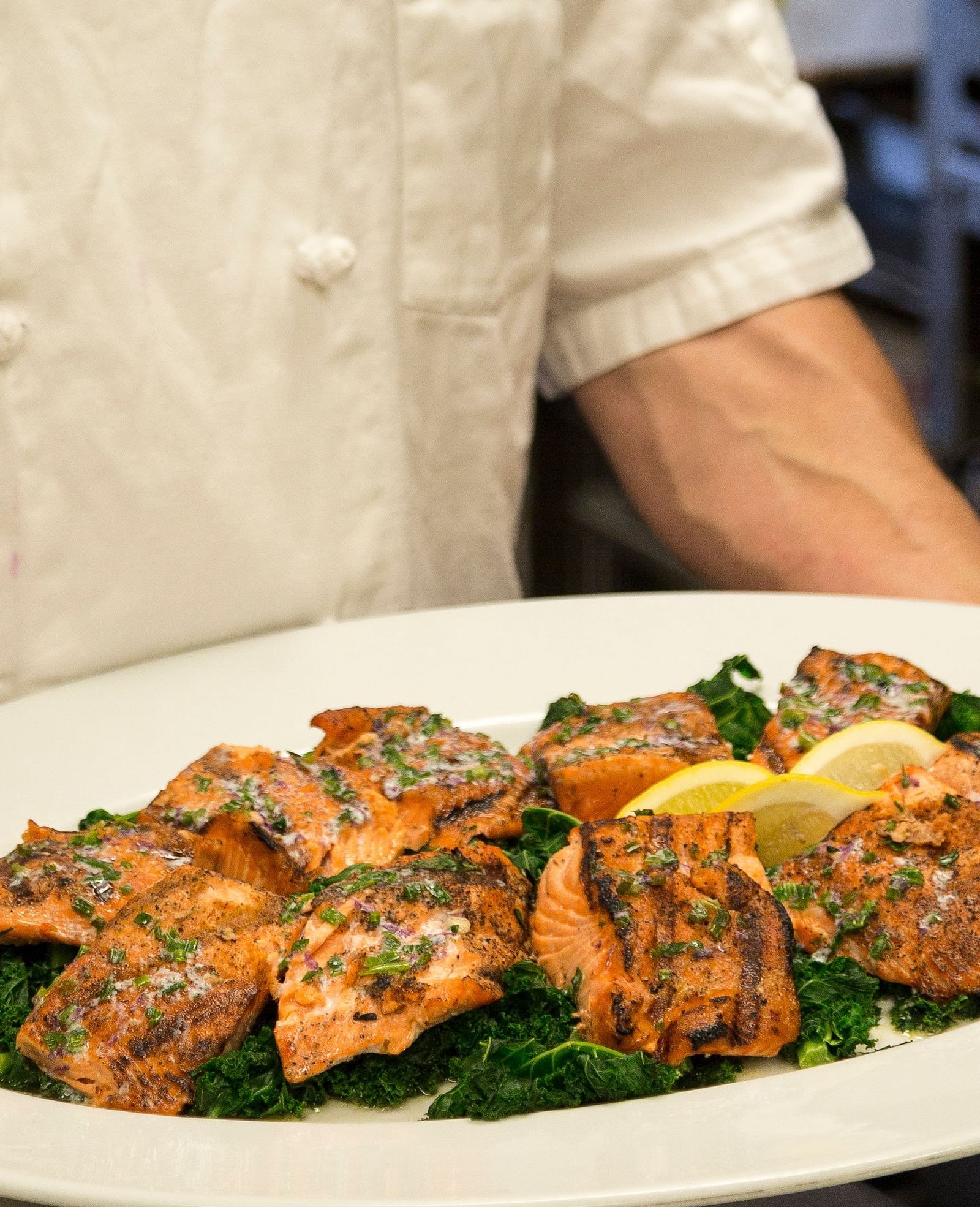 A chef carrying a Salmon dish on a white plate - Brewery Gulch Inn & Spa