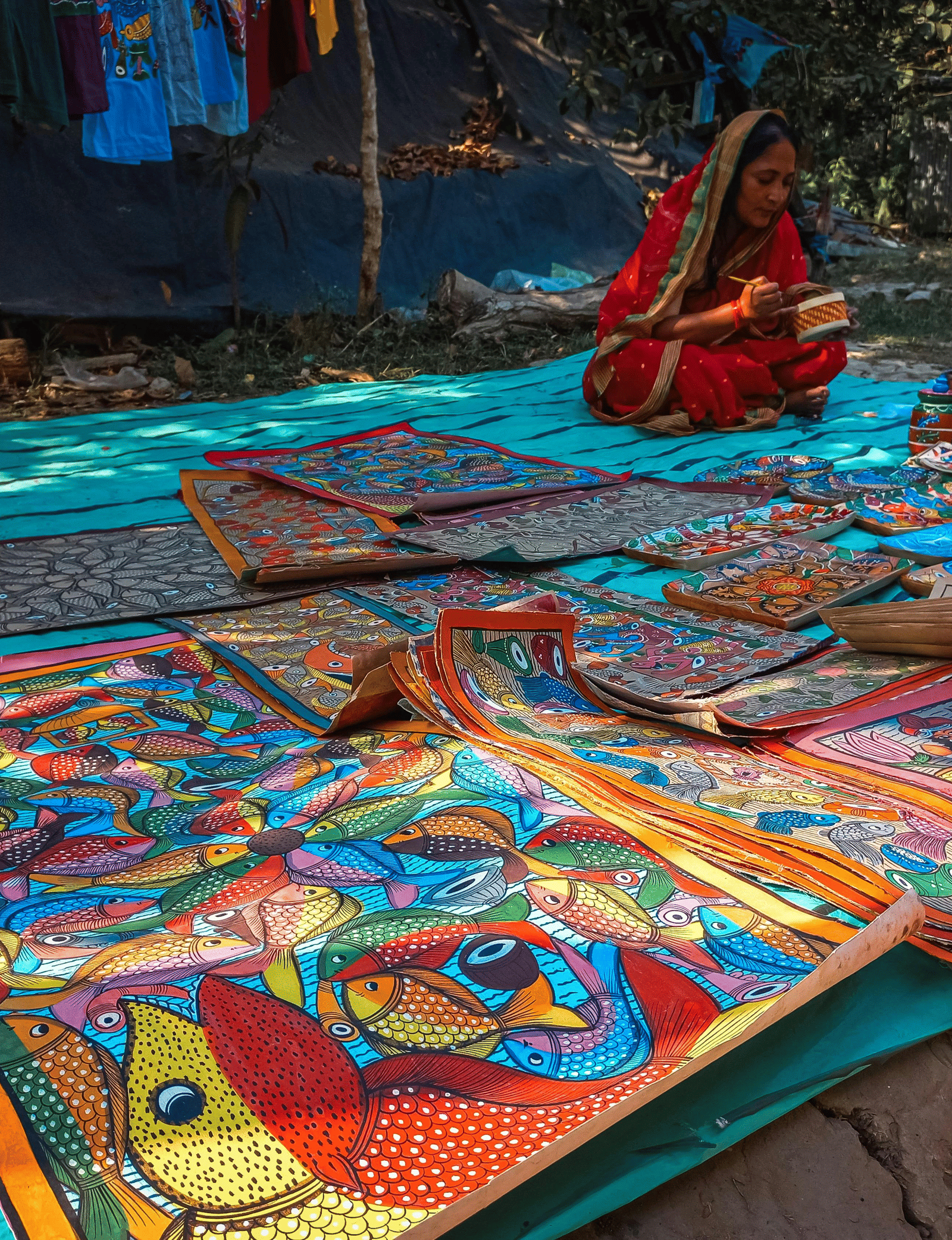 Display of colourful traditional artworks and handicrafts arranged on a street market stall.