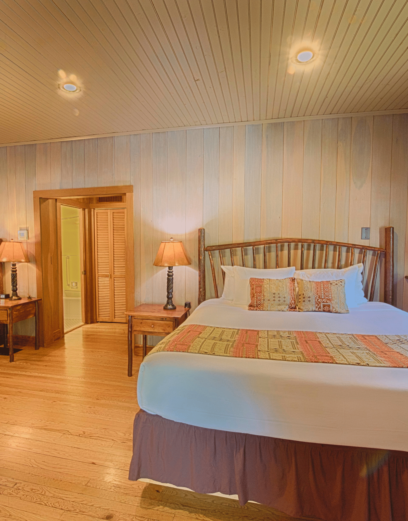 front view image of a double bed in a bedroom with two bed side tables on the either side of it - Historic Tapoco Lodge