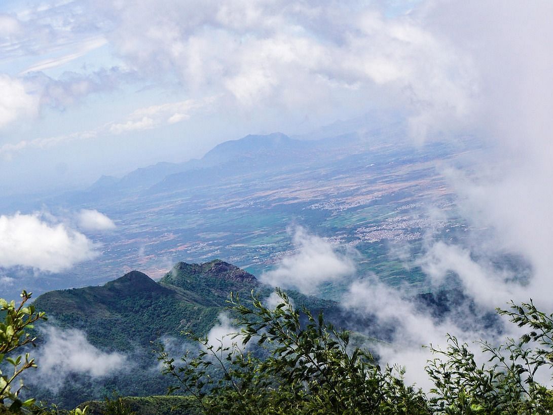 An aerial view of a mountainous landscape with clouds floating around.