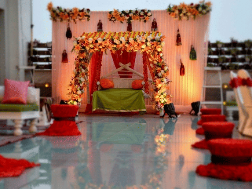 Elegant wedding mandap setup at Ramada Plaza by Wyndham Palm Grove, featuring floral decor, warm lighting, and floor seating arranged along a reflective aisle.