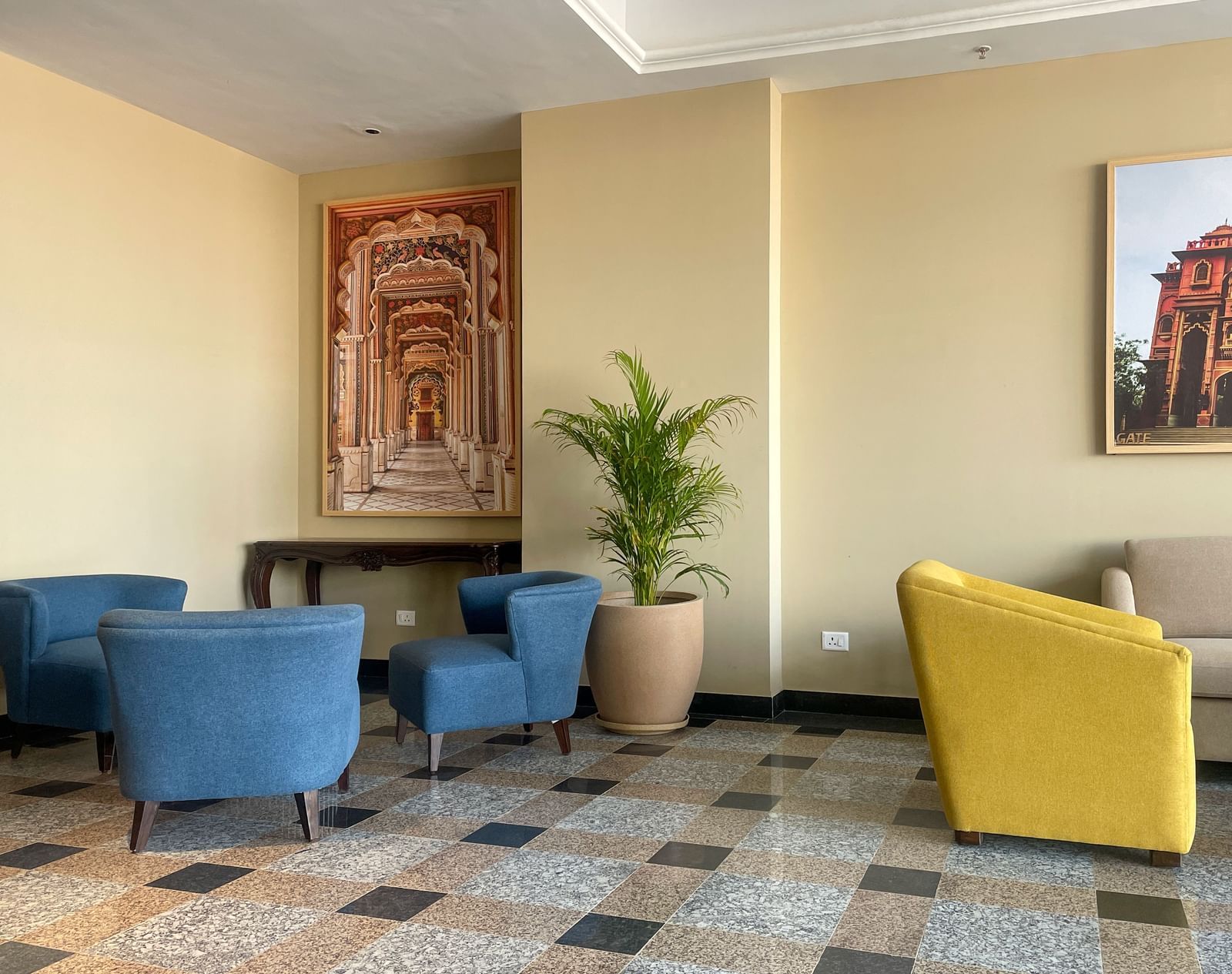 A hotel lobby seating area with blue and yellow armchairs, a couch, a framed artwork, and a potted plant - Urban Suites by BluSalzz, Jaipur