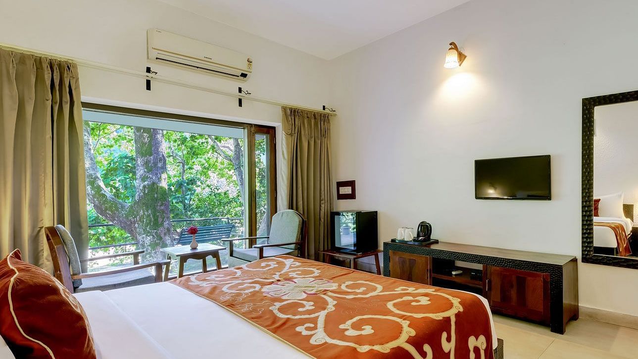 Image of a family room with bed a larg mirror at Summit By The Ganges Beach Resort & Spa, Rishikesh