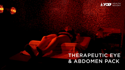 Person relaxing in a dimly lit spa room during a Therapeutic Eye & Abdomen Pack treatment at YO1 Longevity & Health Resorts
