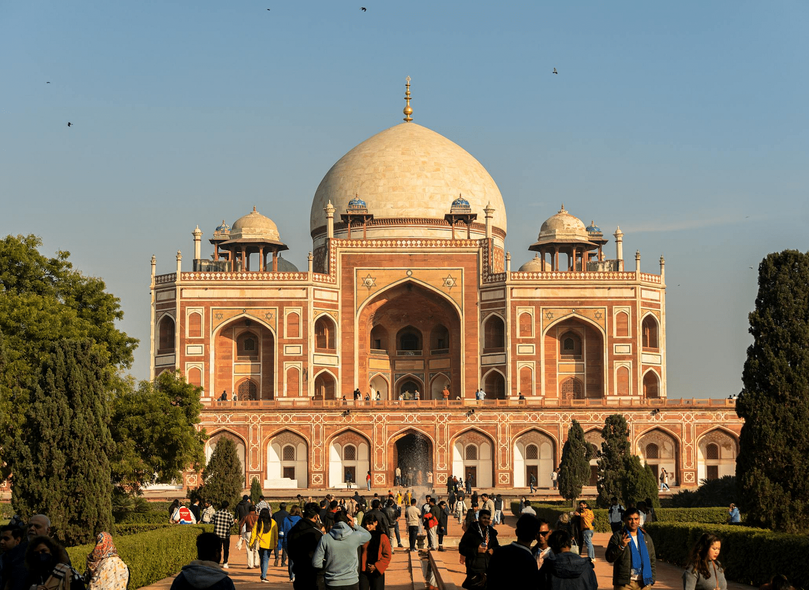 Front view of Humayuns-tomb with people and tress in front of it.