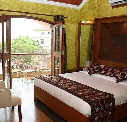 Room featuring a double bed and a balcony with seating area