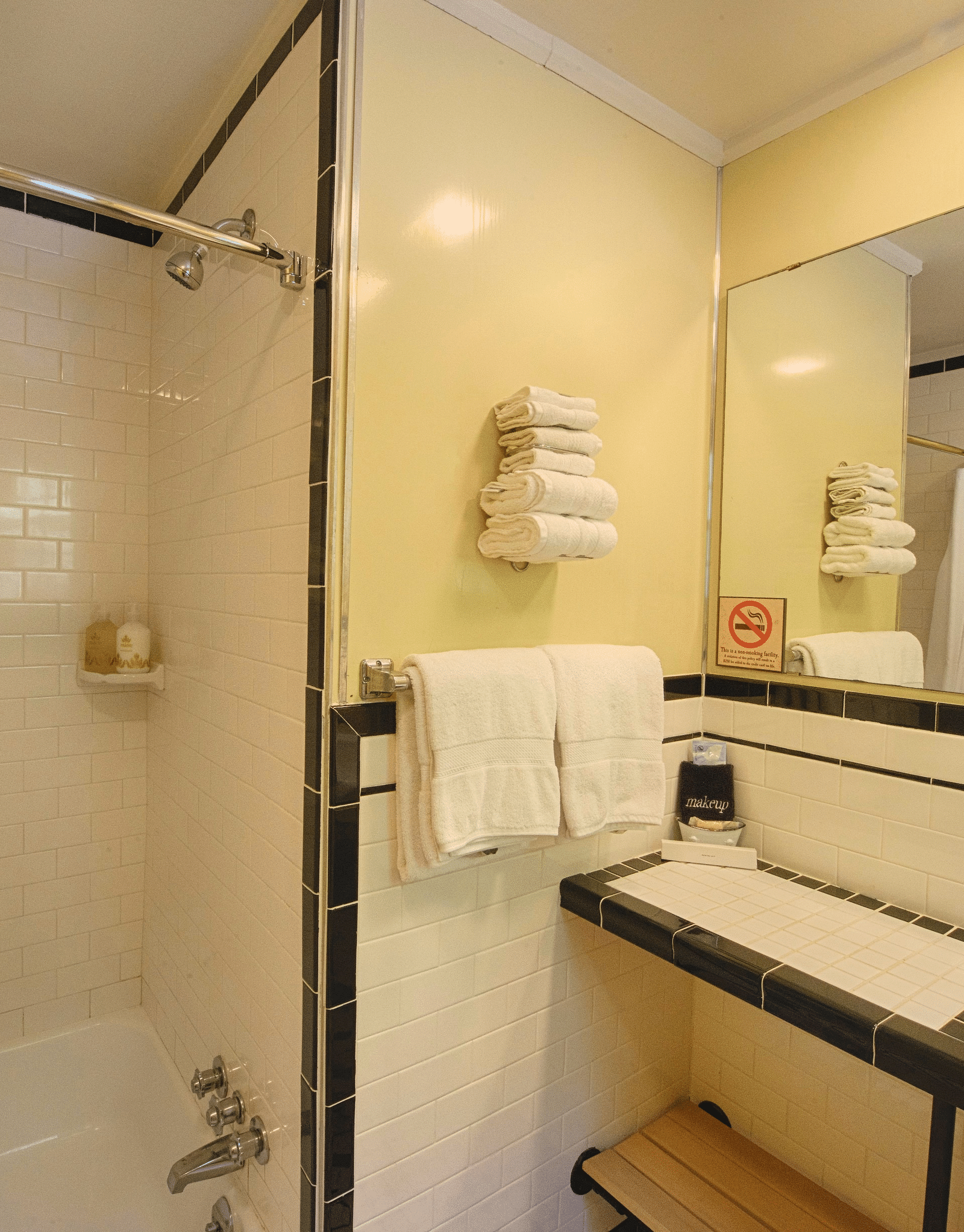 a close up image of a bathroom with a bathtub and a wash basin along with a wide mirror and fresh towels hanging on the side - Historic Tapoco Lodge