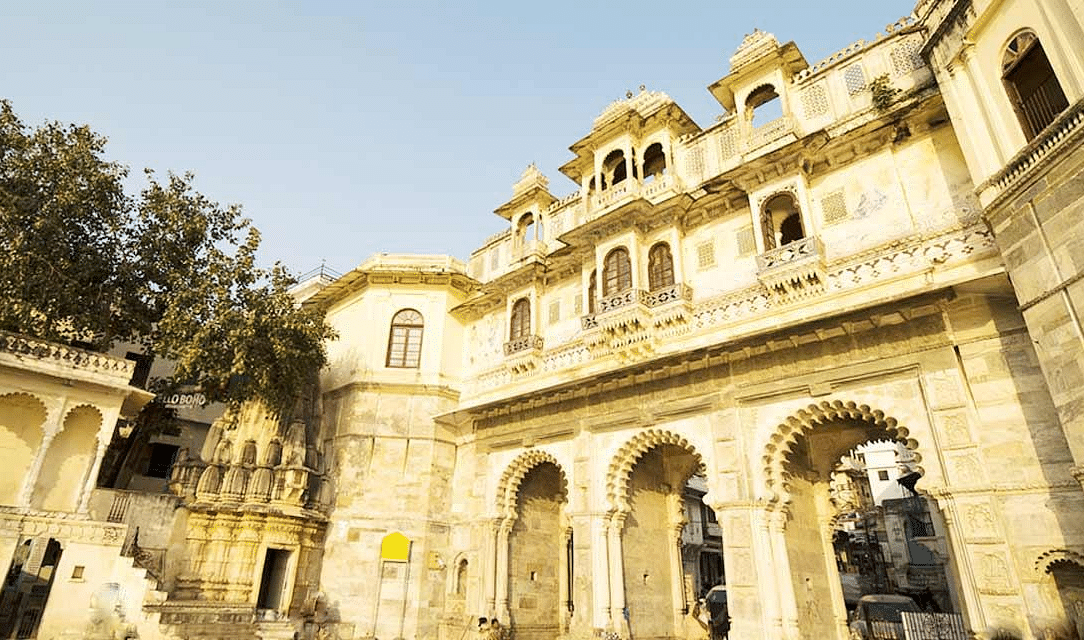 A low-angle shot of a grand building with arched doorways and balconies, under a bright sky.