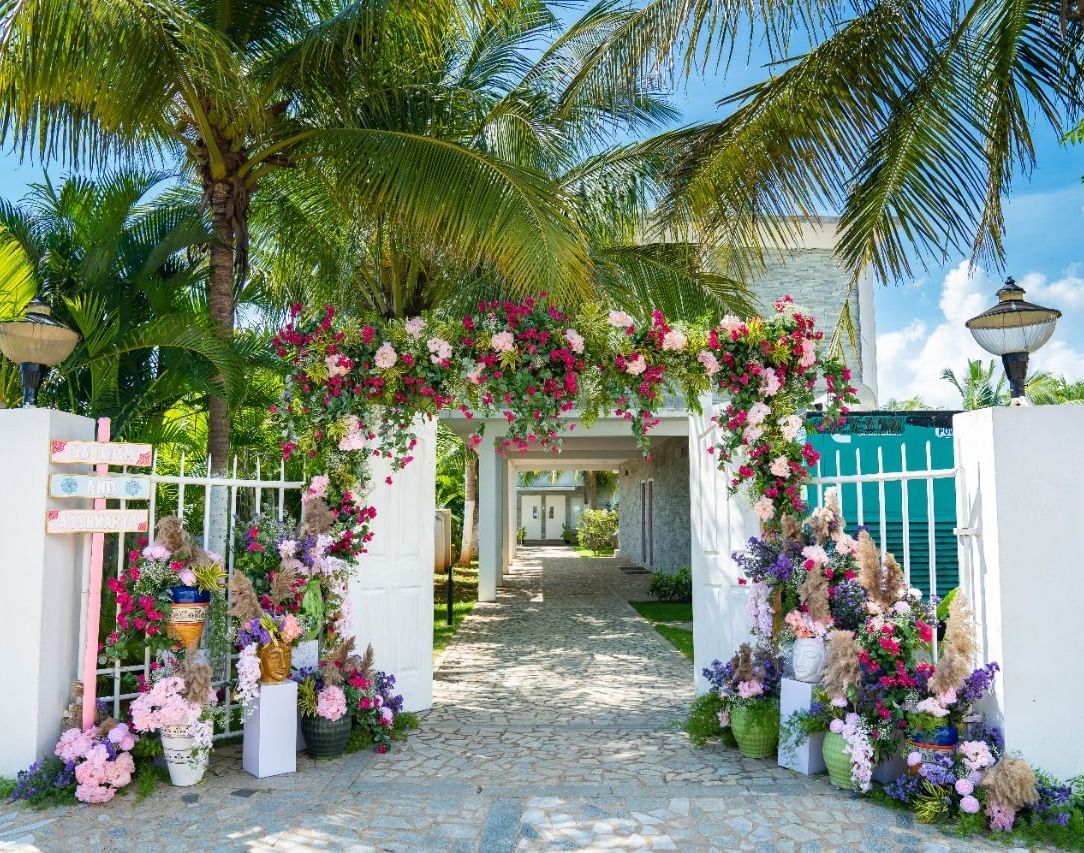 An elegant outdoor archway decorated with purple and white flowers, leading into a light-colored building | Grande Pavillion | Grand Bay Resort and Spa