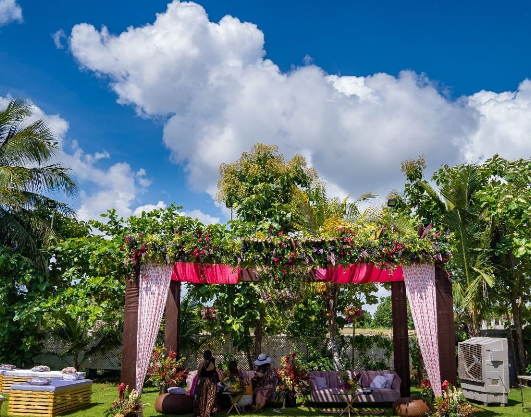 An outdoor wedding canopy or mandap decorated with pink and white fabrics and flowers, set on a green lawn under a bright blue sky | Grande Pavillion | Grand Bay Resort and Spa