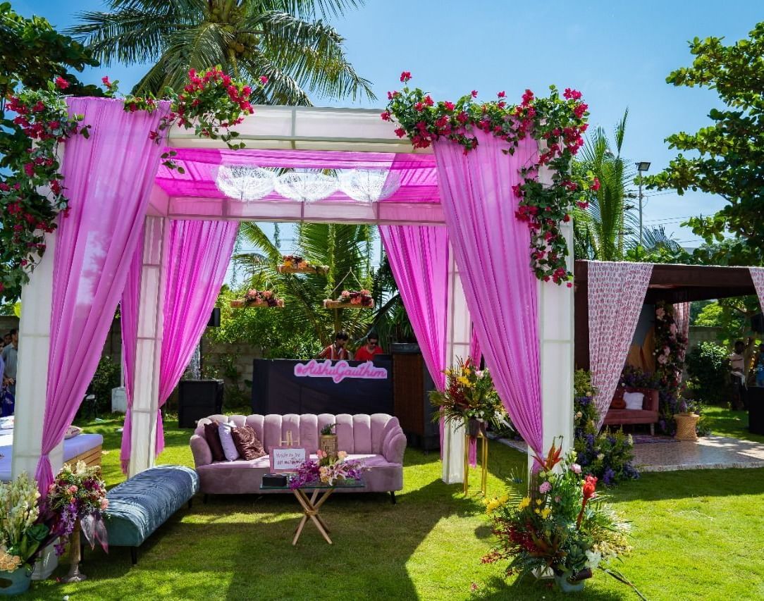 A beautifully decorated outdoor wedding canopy or mandap with pink and white flowers and fabric, set on a green lawn | Grande Pavillion | Grand Bay Resort and Spa