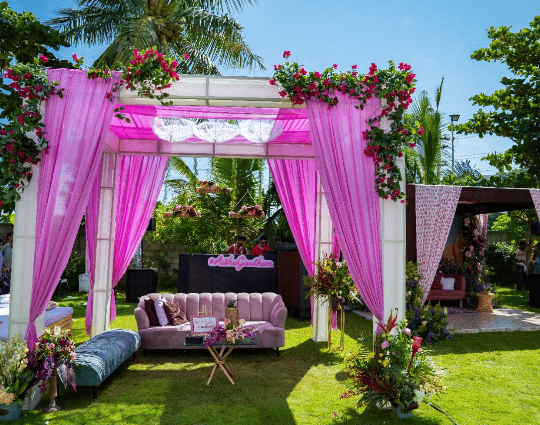 A beautifully decorated outdoor wedding canopy or mandap with pink and white flowers and fabric, set on a green lawn - Grande Bay Resort & Spa, Mamallapuram