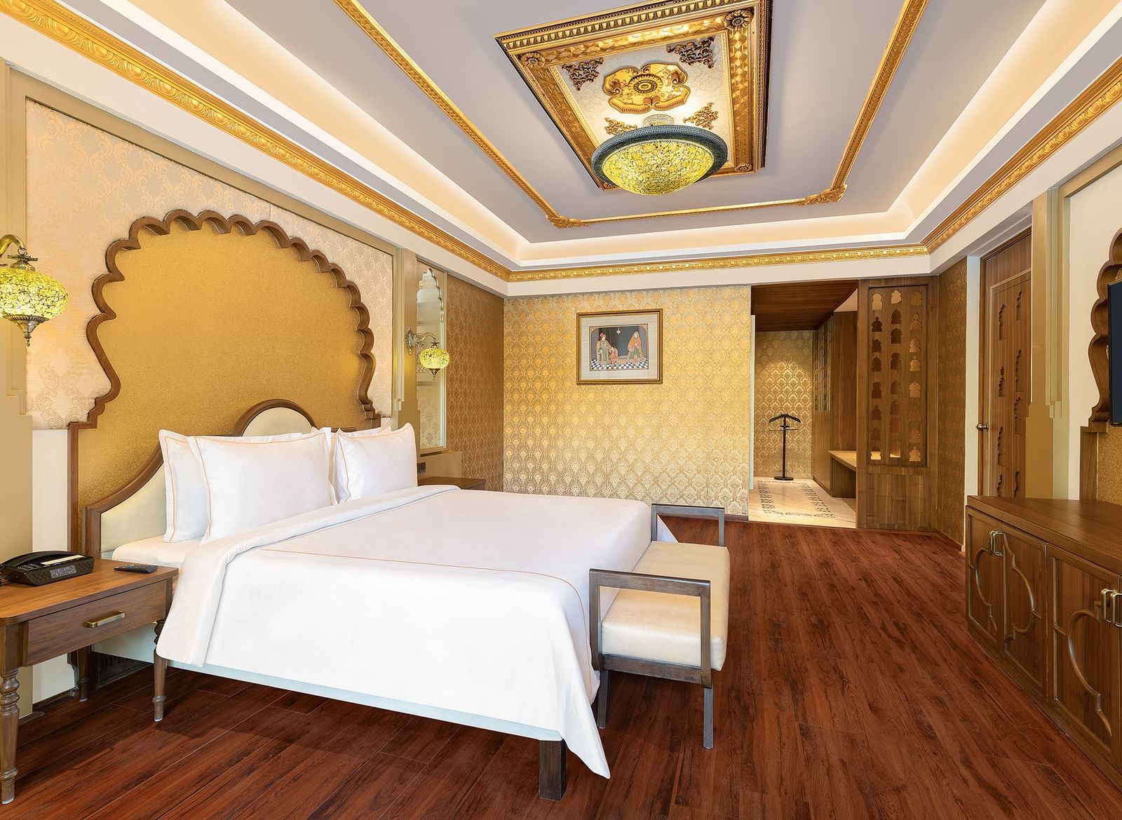 A spacious bedroom with clean white linen and ornate gold frames above the beds – Kaldan Samudra, one of the best luxury hotels in Mahabalipuram