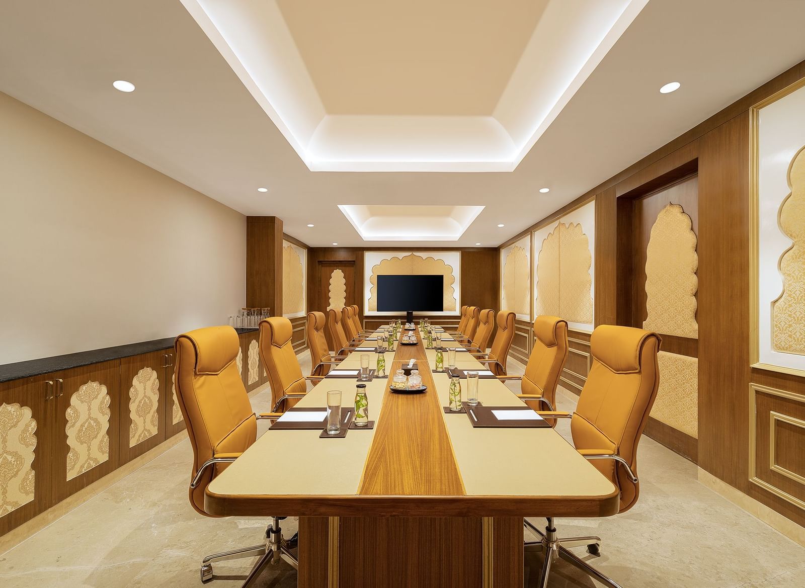 A boardroom in Mahabalipuram with a long table, cosy orange chairs, and rajasthani decor - Kaldan Samudhra Palace