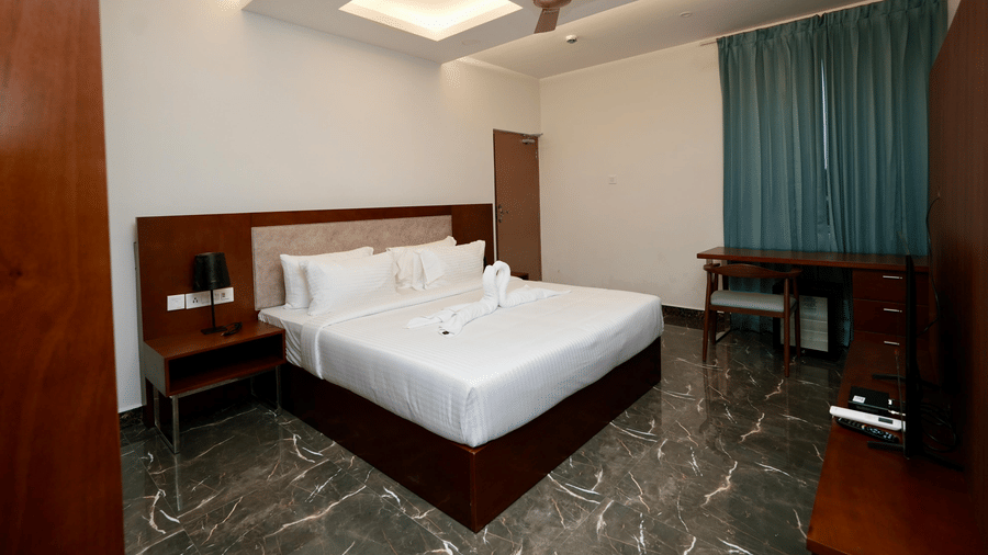 A refined Family Suite at Le Royale Palace with a king-size bed, marble flooring, and a well-arranged wooden desk setup