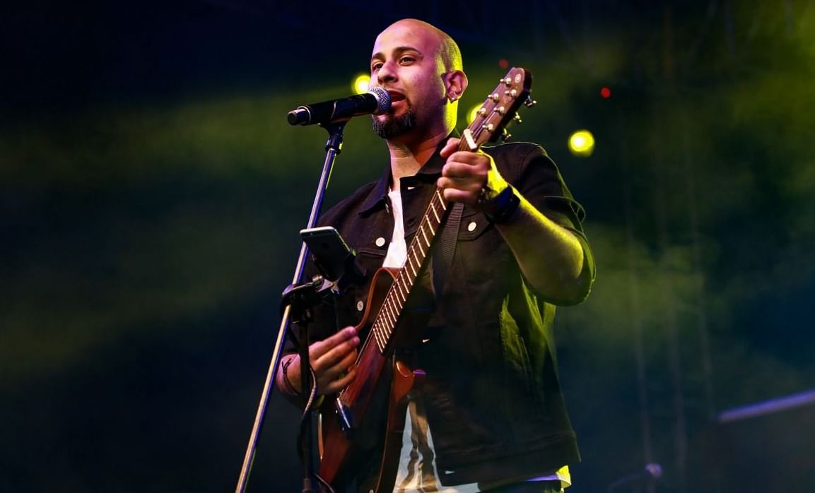 A musician wearing a stylish vest passionately plays a guitar on stage
