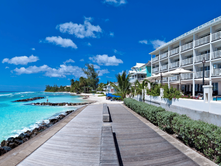 Oceanfront pathway beside The Soco Hotels with clear turquoise water seen during a bright sunny sky.
