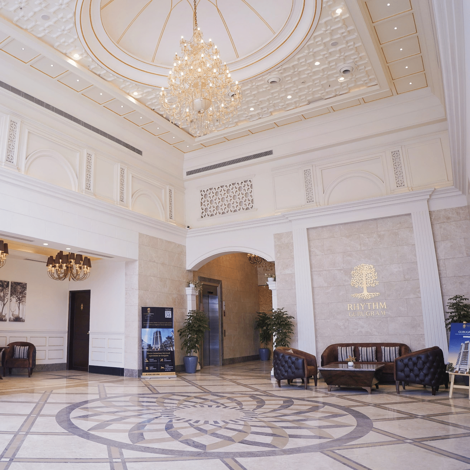 Seating arrangements inside the lobby with a chandelier above - Rhythm Gurugram